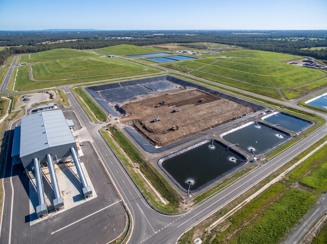 Engineered waste management site with a lined active cell, capped and grassed cells, leachate ponds and a processing building